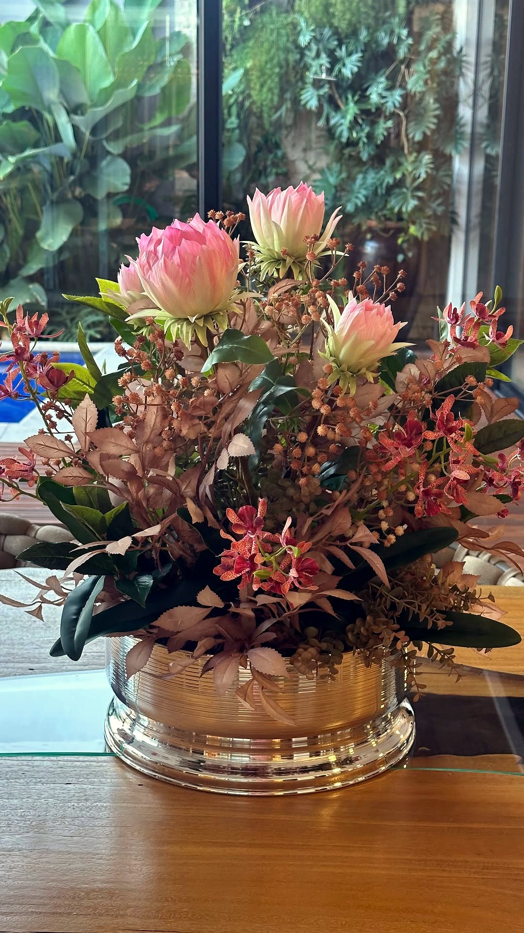 Arranjo de flores permanentes em vaso de prata, sobre aparador decorado da Mati Taperê